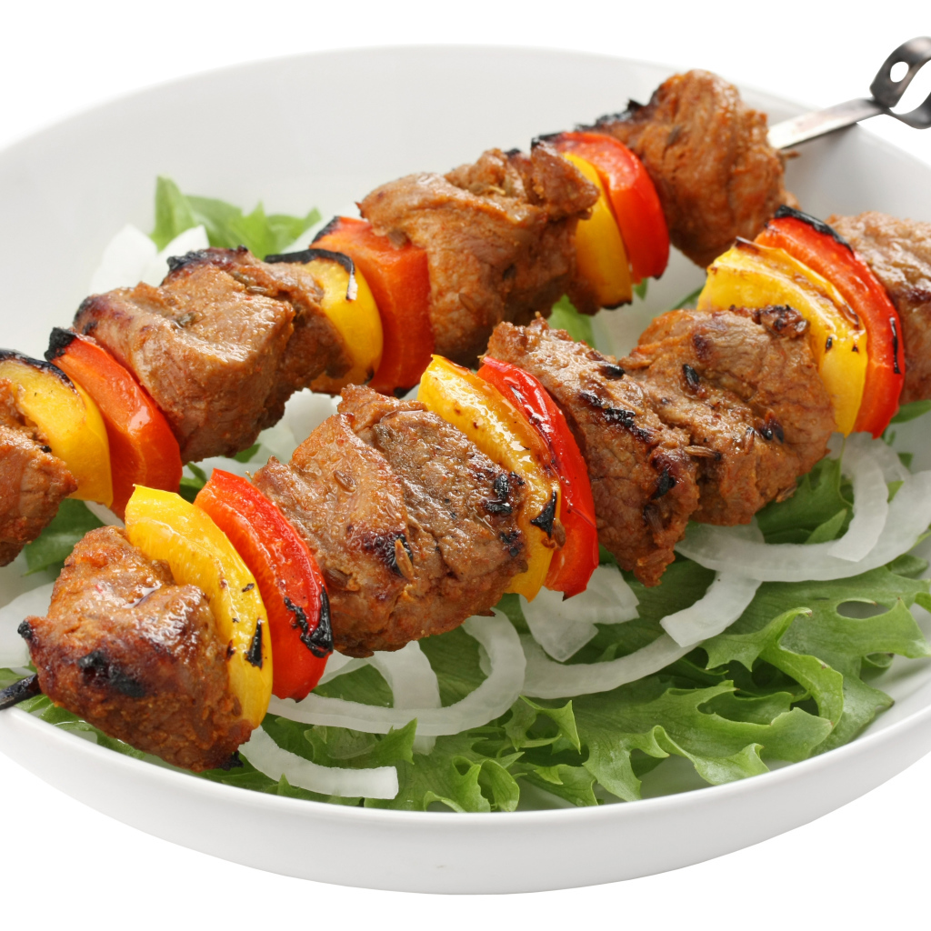 Shish kebab with bell pepper on a plate with lettuce.