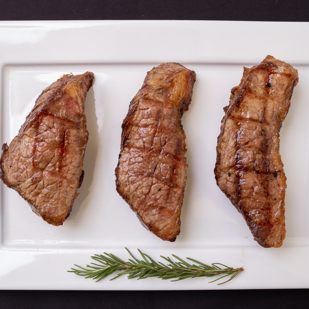 Три куска жареного мяса на большой белой тарелке