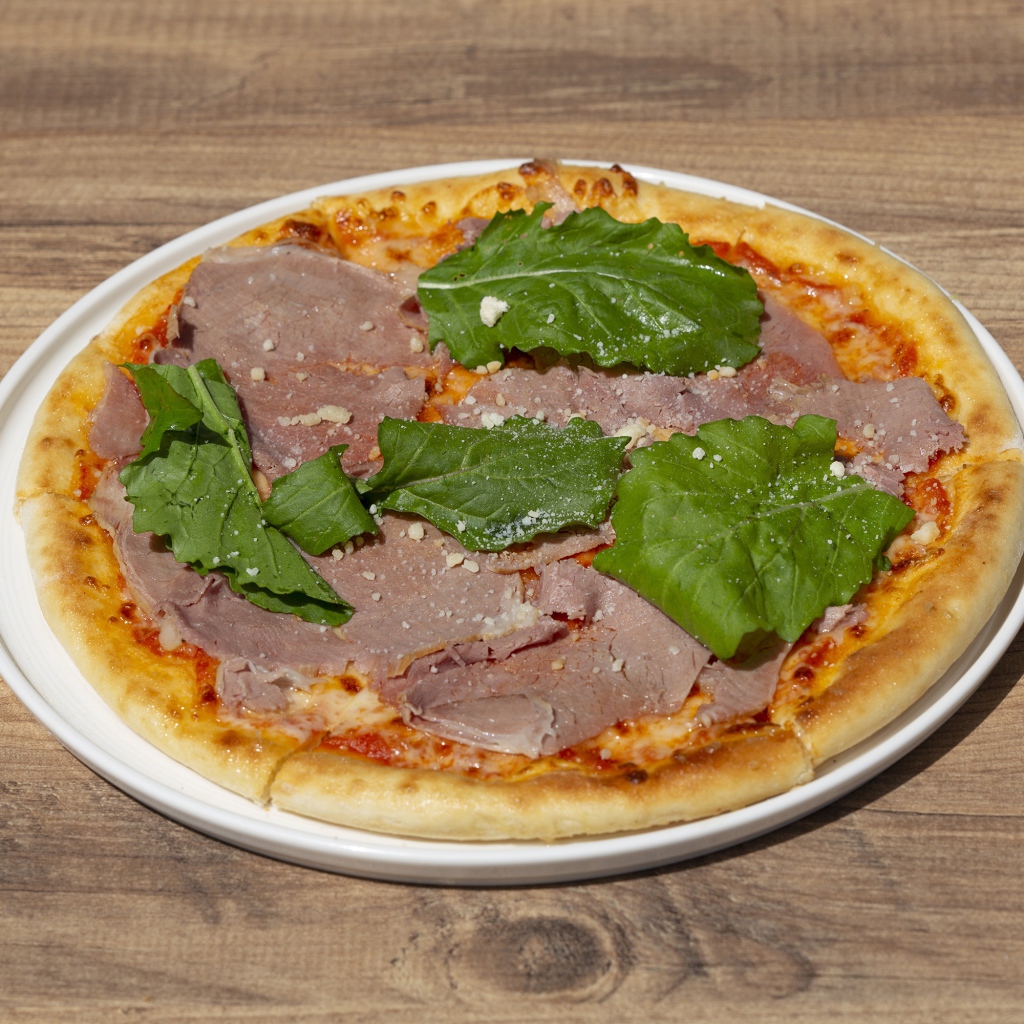 Пицца с кусочками мяса и зеленью на столе