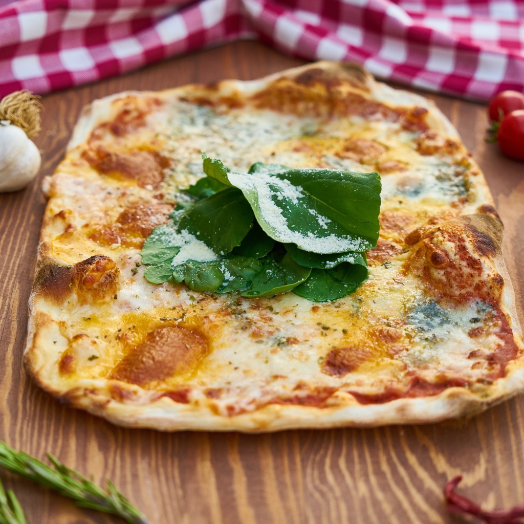 Румяная пицца на столе с овощами