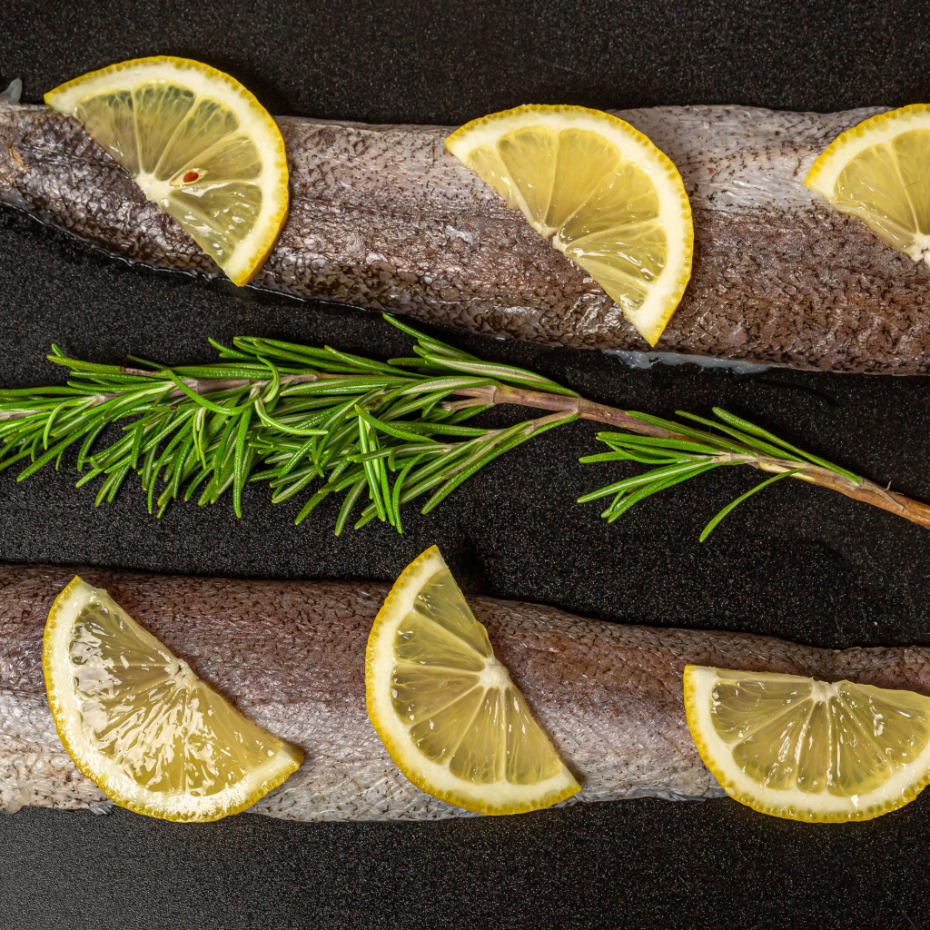 Свежее филе рыбы с лимоном и розмарином на черном фоне