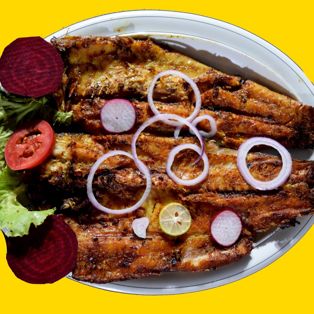 Жареная рыба с листьями салата, помидорами и свеклой на желтом фоне