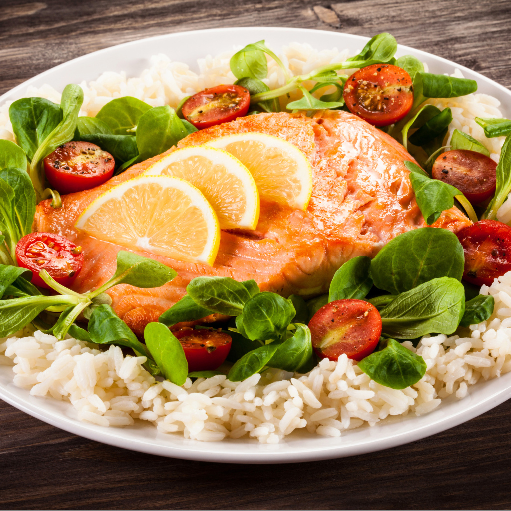 Piece of fish on a plate with tomatoes, rice and basil leaves