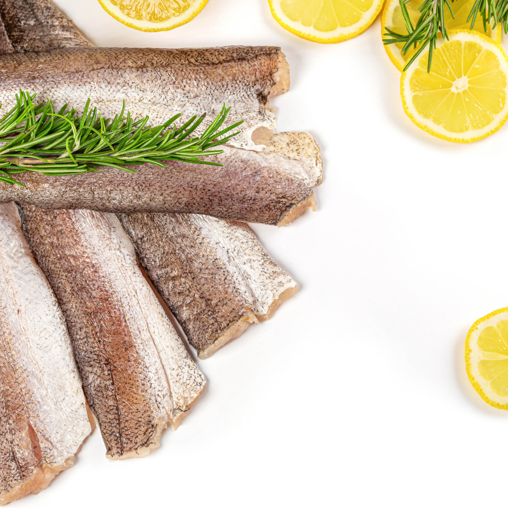 Raw fish with rosemary and lemon on a white plate