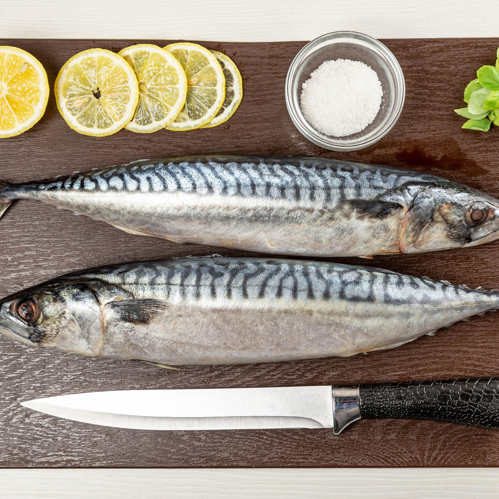 Two fresh mackerels on a board with lemon