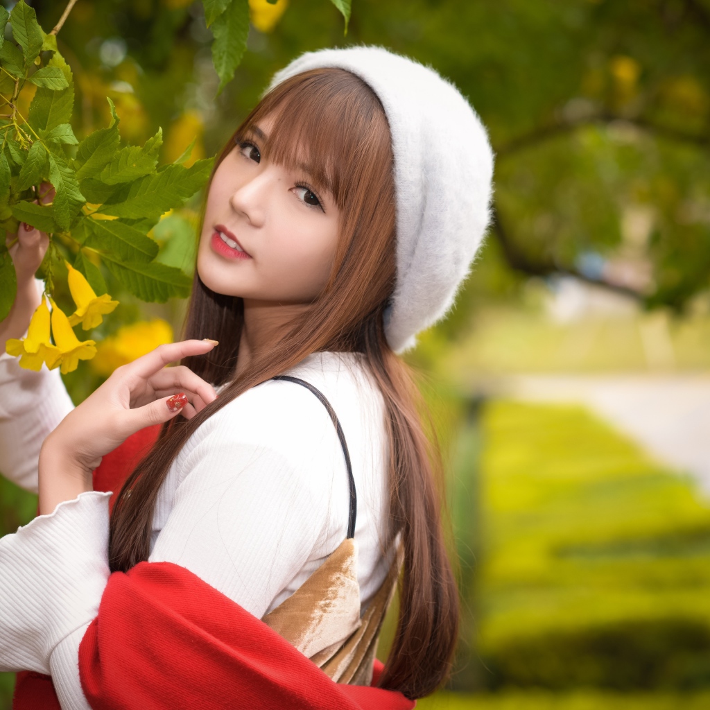 Девушка в берете стоит у куста с желтыми цветами