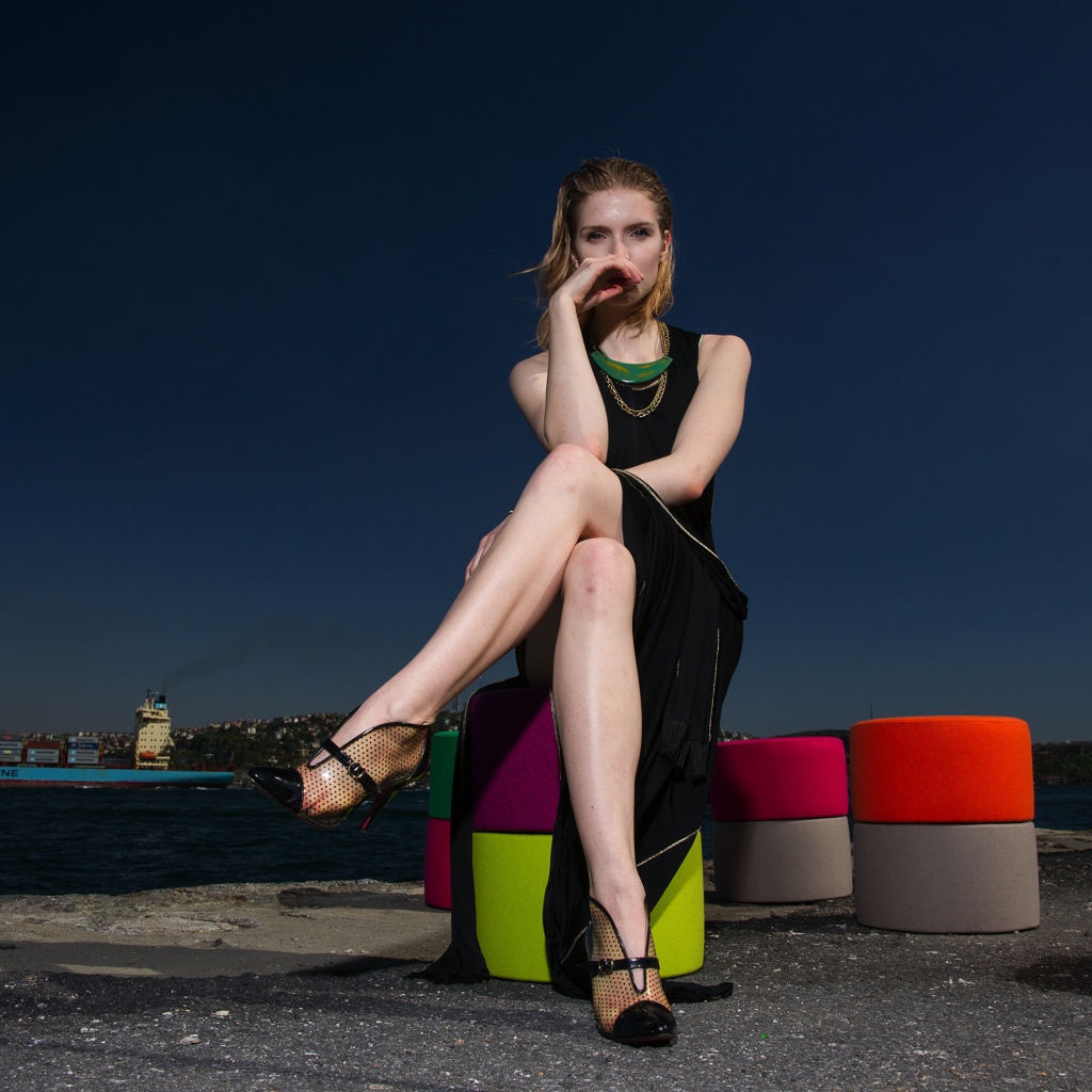 Девушка в черном платье сидит у воды