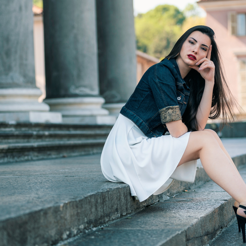 Девушка в белом платье сидит на ступеньках