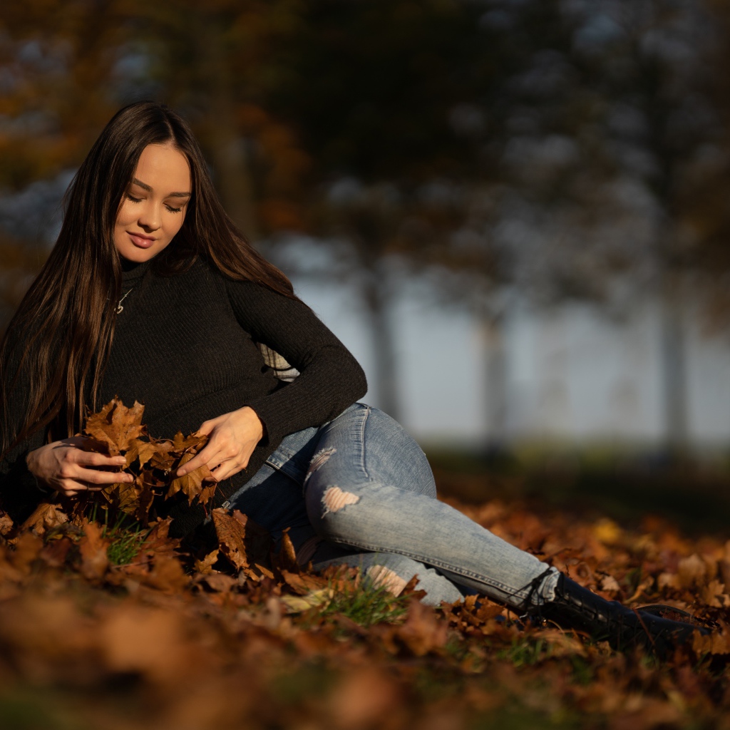 Молодая девушка лежит на опавшей листве