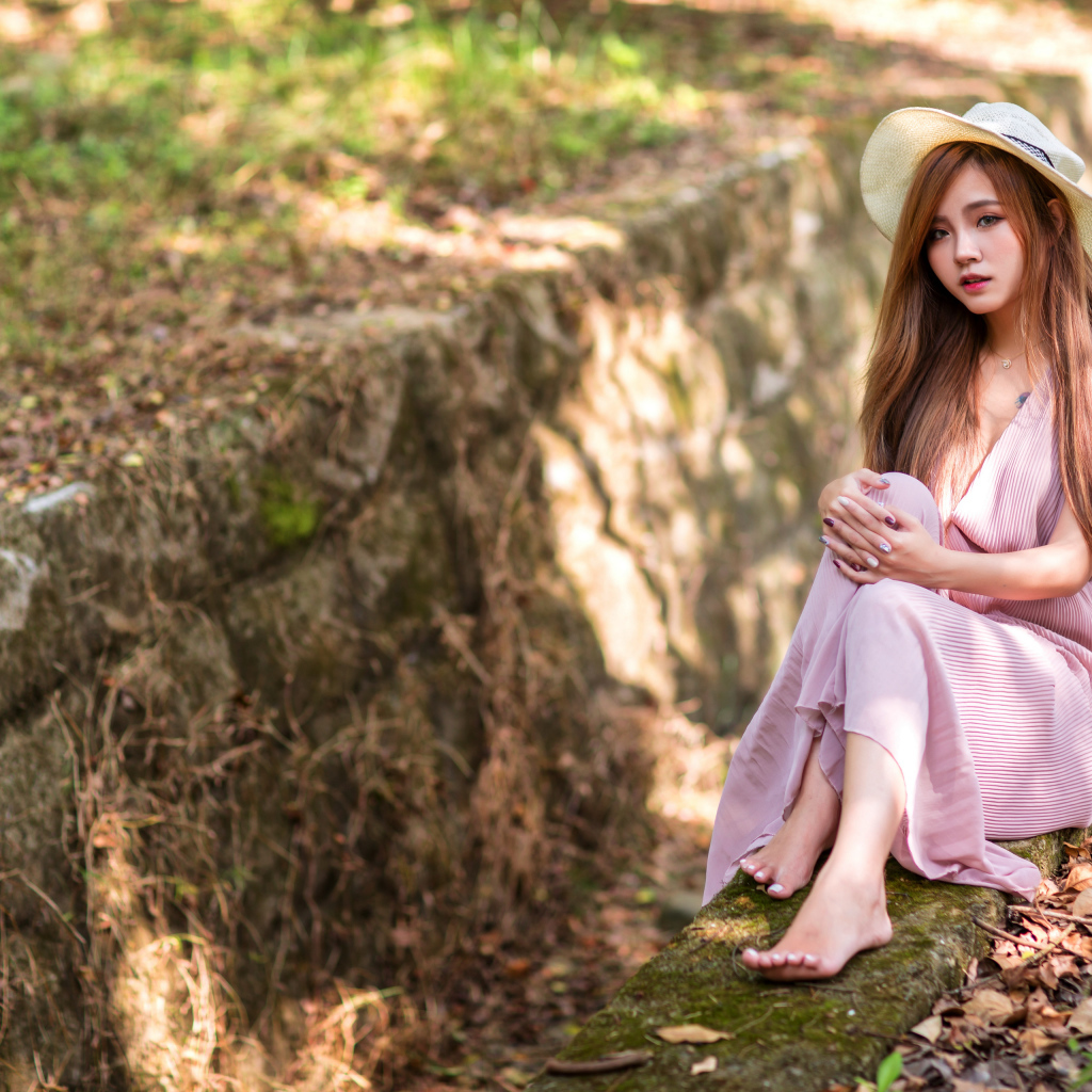 Девушка азиатка в розовом платье сидит на земле