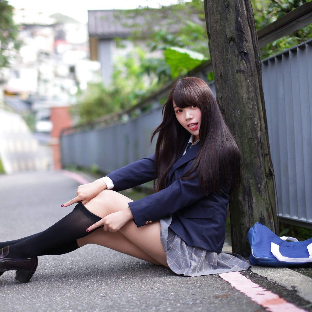 Девушка азиатка в черных чулках сидит у дерева