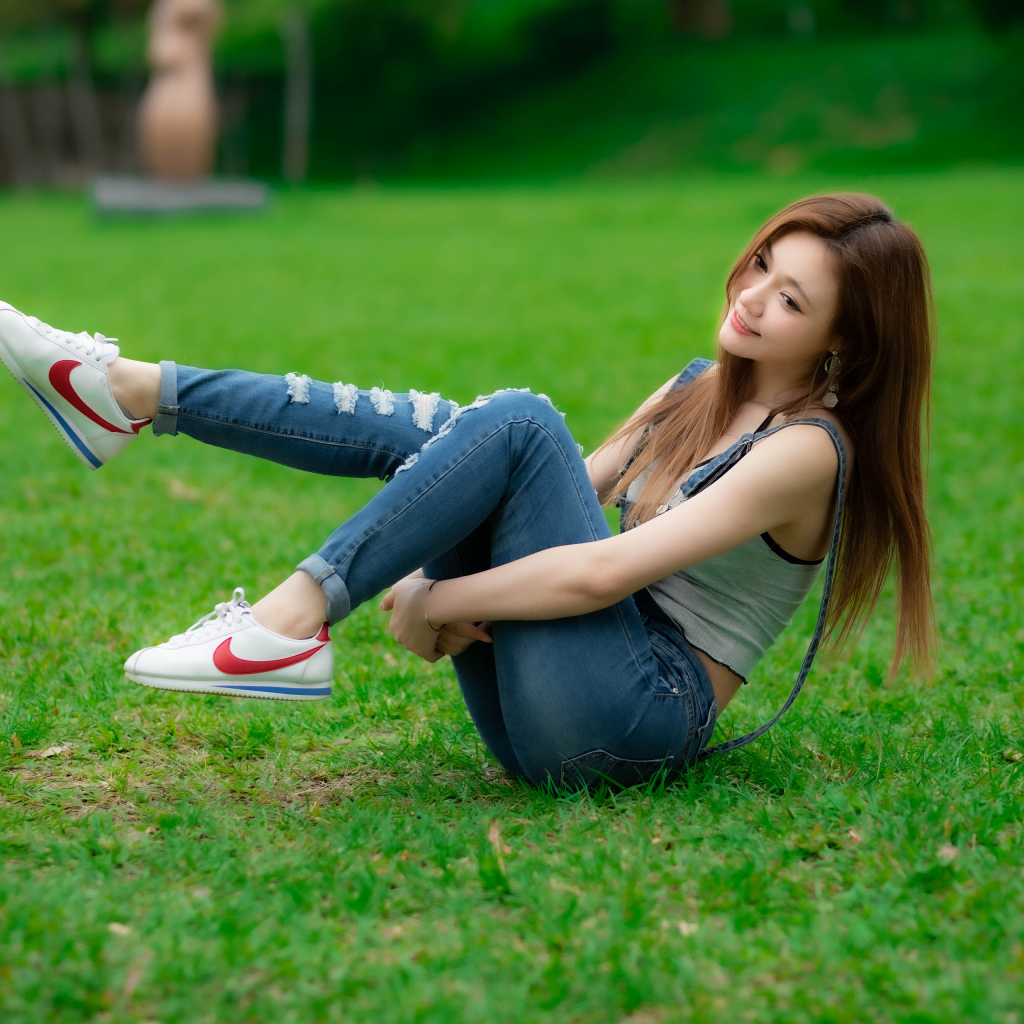 Девушка азиатка лежит в парке на траве