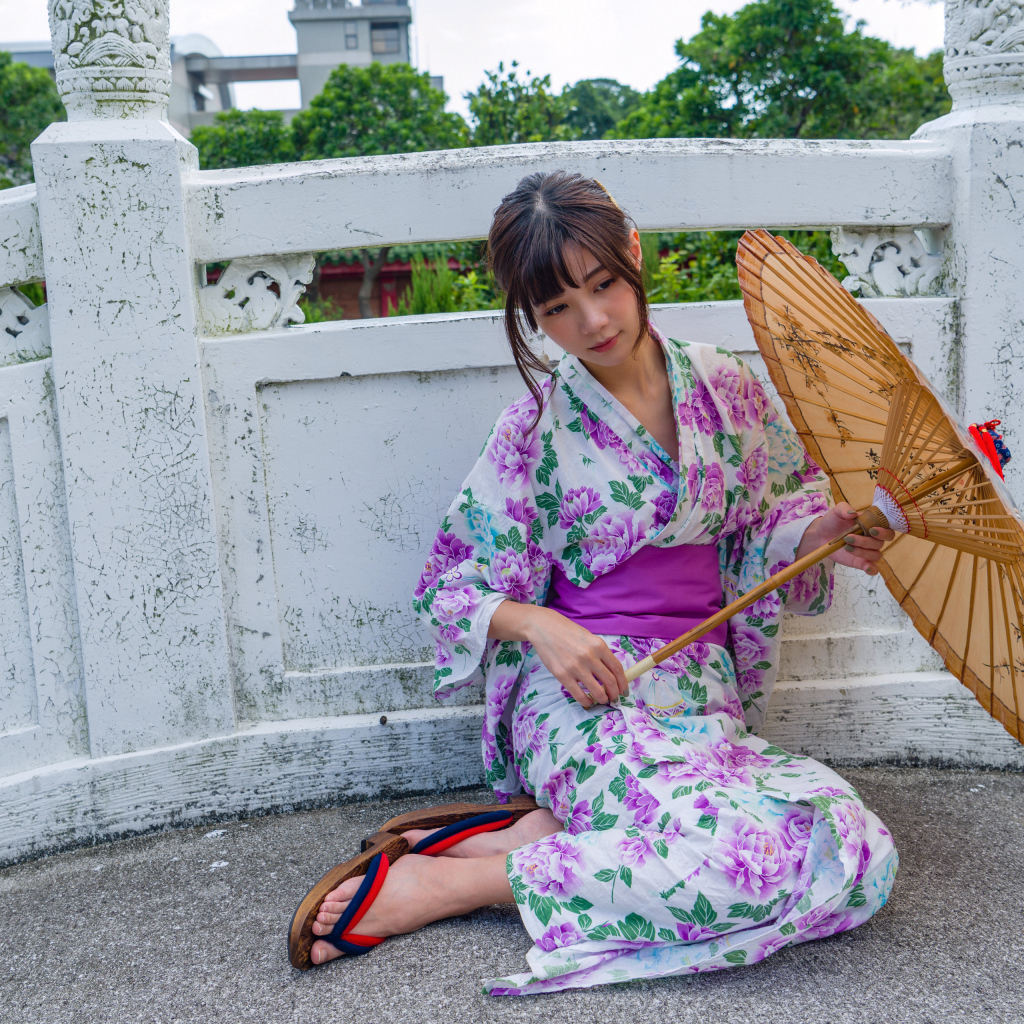 Девушка азиатка сидит в кимоно с зонтом 