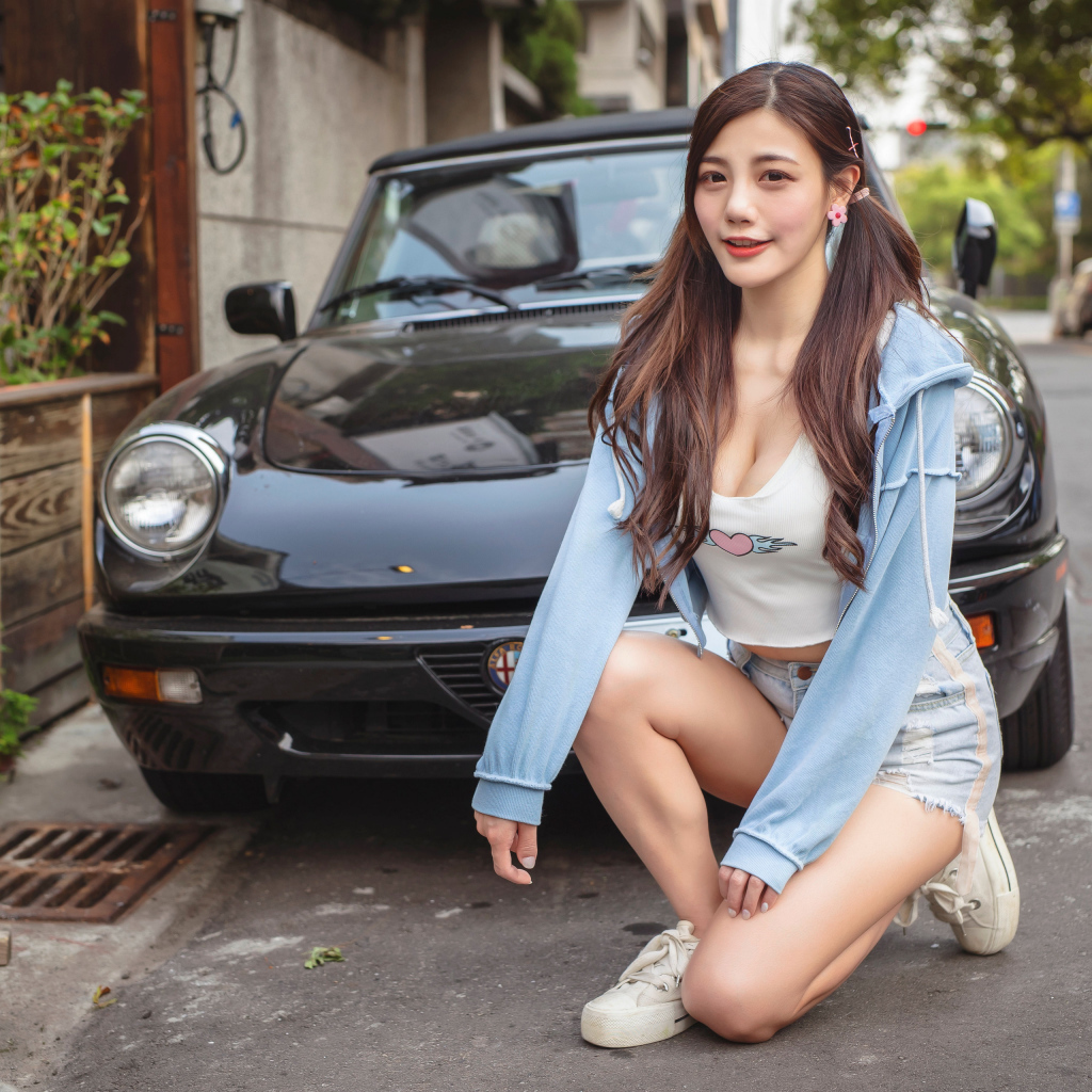 Девушка азиатка сидит возле машины 