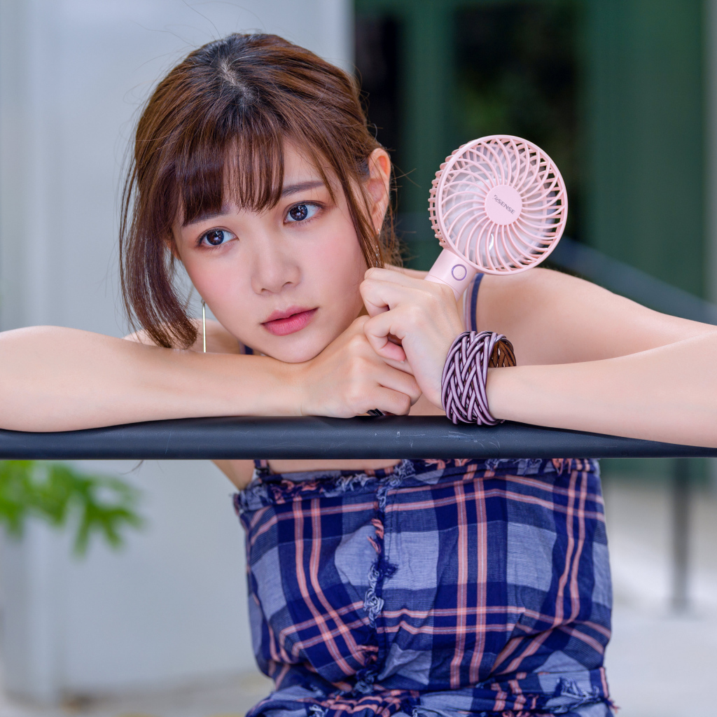 Девушка азиатка с вентилятором в руке 