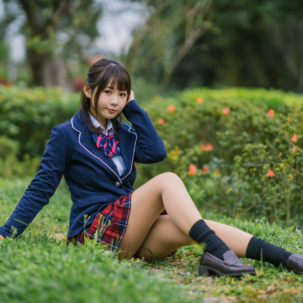 Азиатская школьница сидит на траве