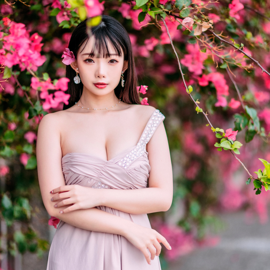 Красивая девушка азиатка у куста с  красными цветами 