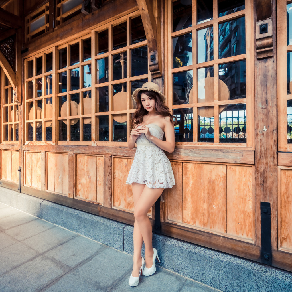 Красивая девушка азиатка стоит у стены с большими окнами