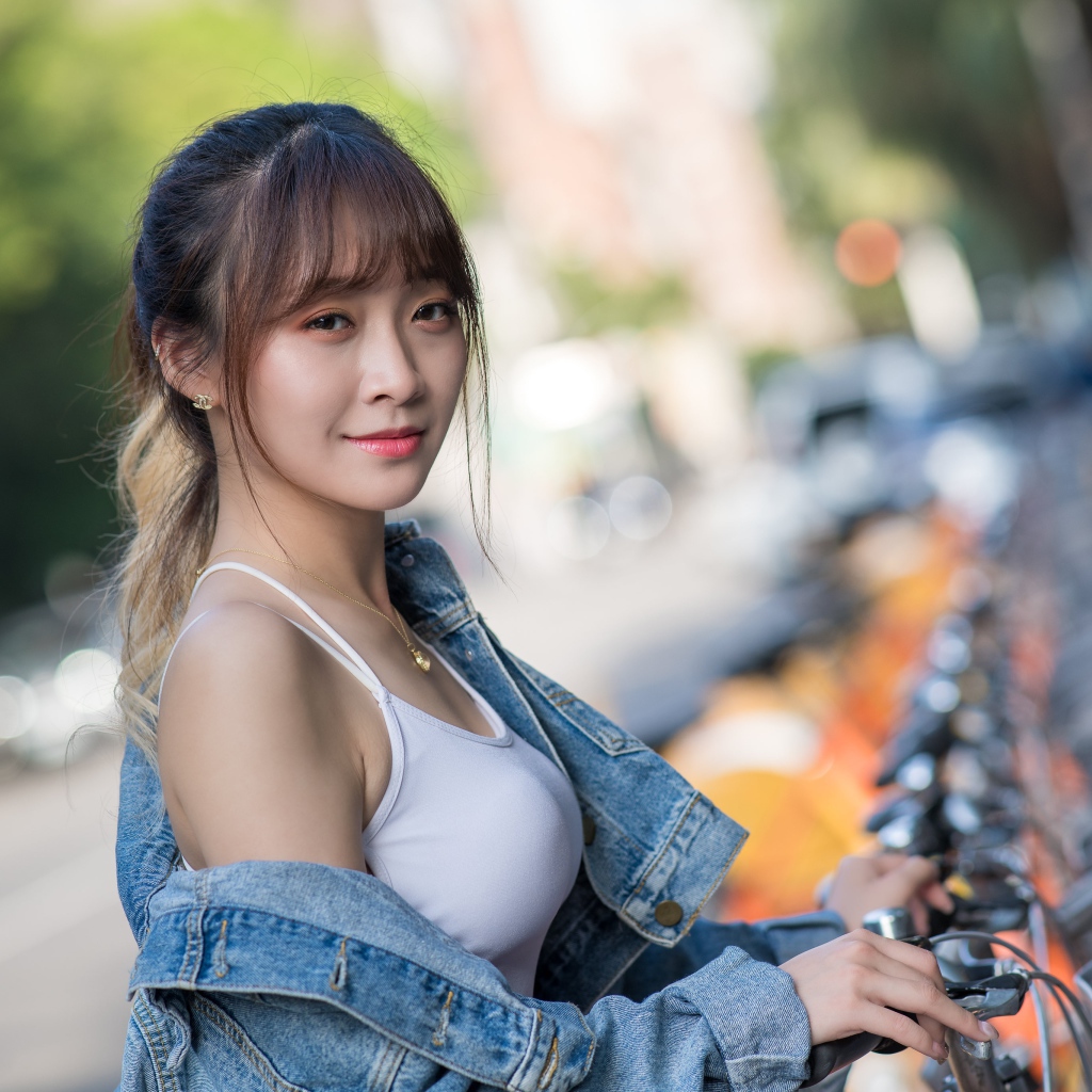 Красивая азиатка в джинсовой куртке с велосипедом