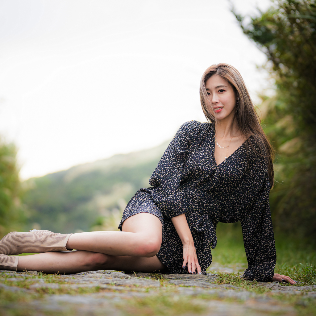 Красивая девушка азиатка в платье лежит на земле 