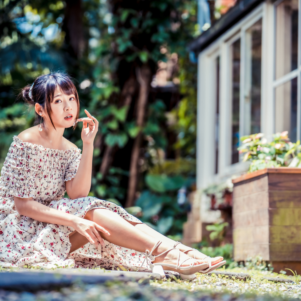 Красивая девушка азиатка в платье сидит на земле