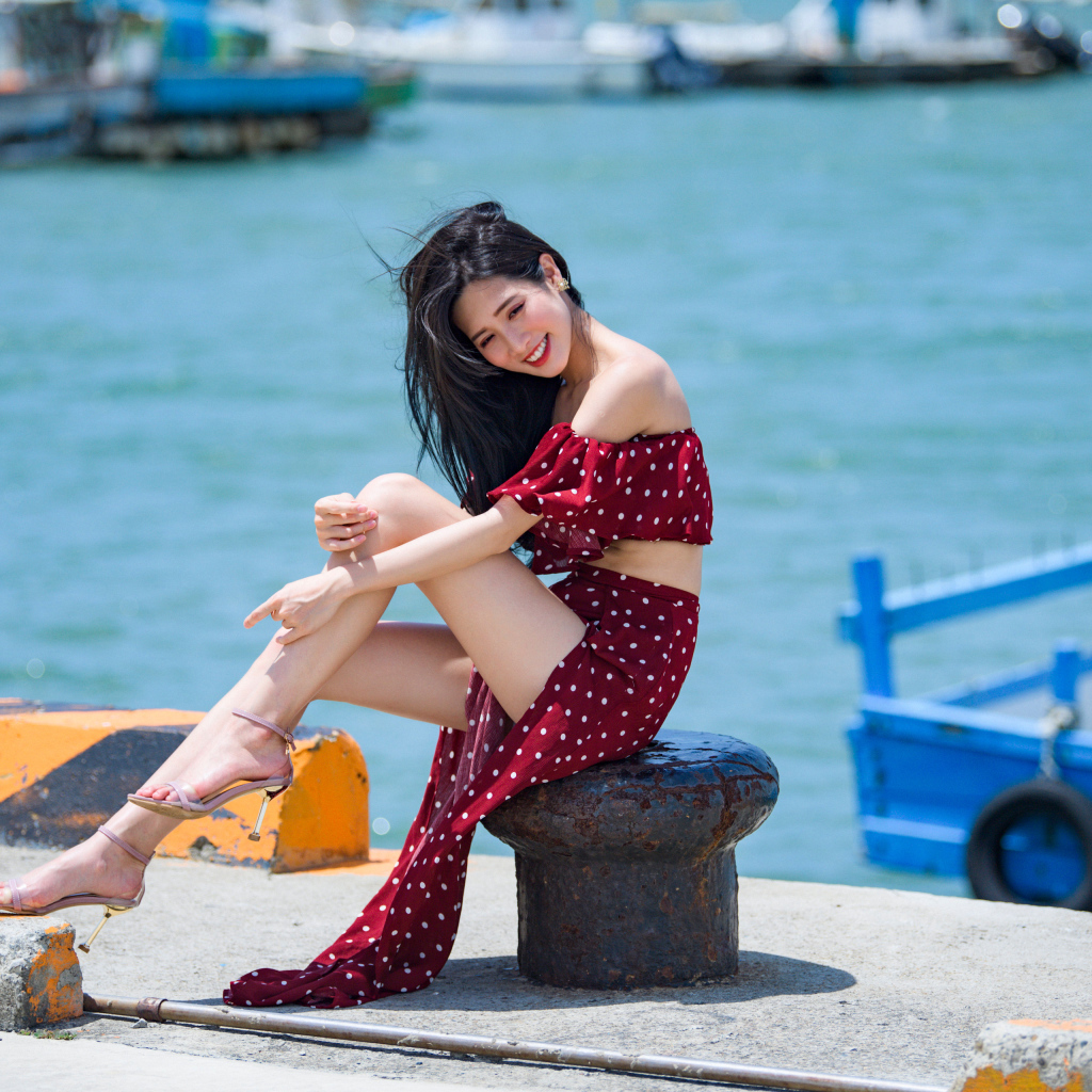 Красивая девушка азиатка в платье в горох у моря