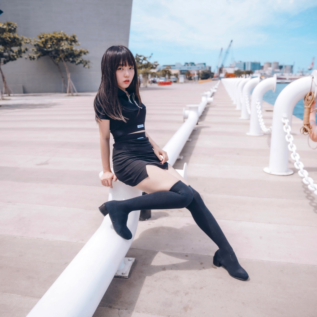 Красивая девушка азиатка в черных сапогах на причале