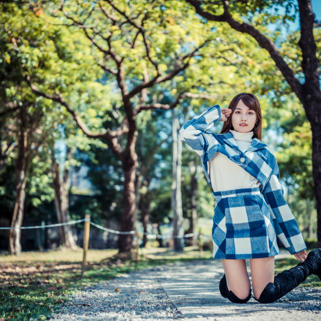 Красивая девушка азиатка стоит на коленях в парке