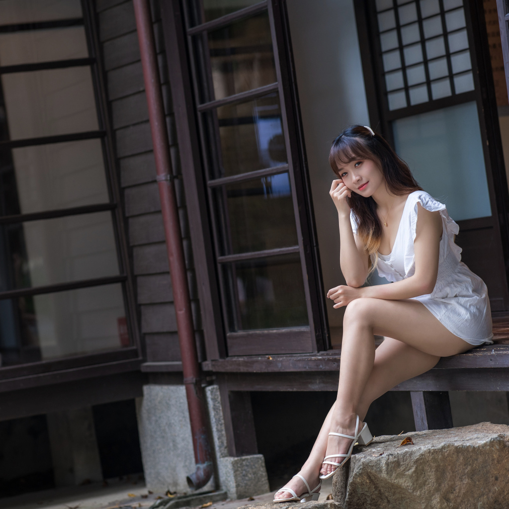 Красивая девушка азиатка сидит у двери