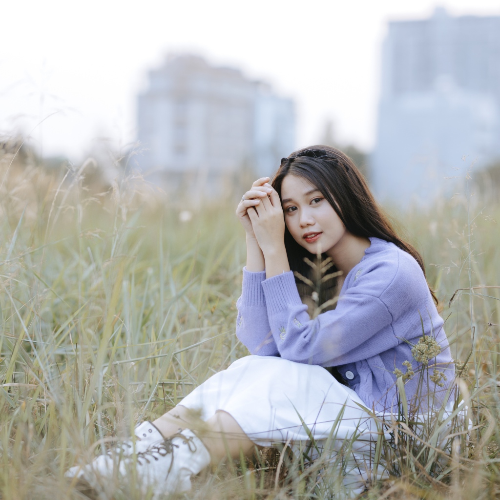 Красивая девушка азиатка сидит на поле с травой 
