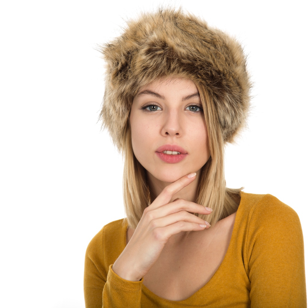 Красивая девушка блондинка в меховой шапке на белом фоне 