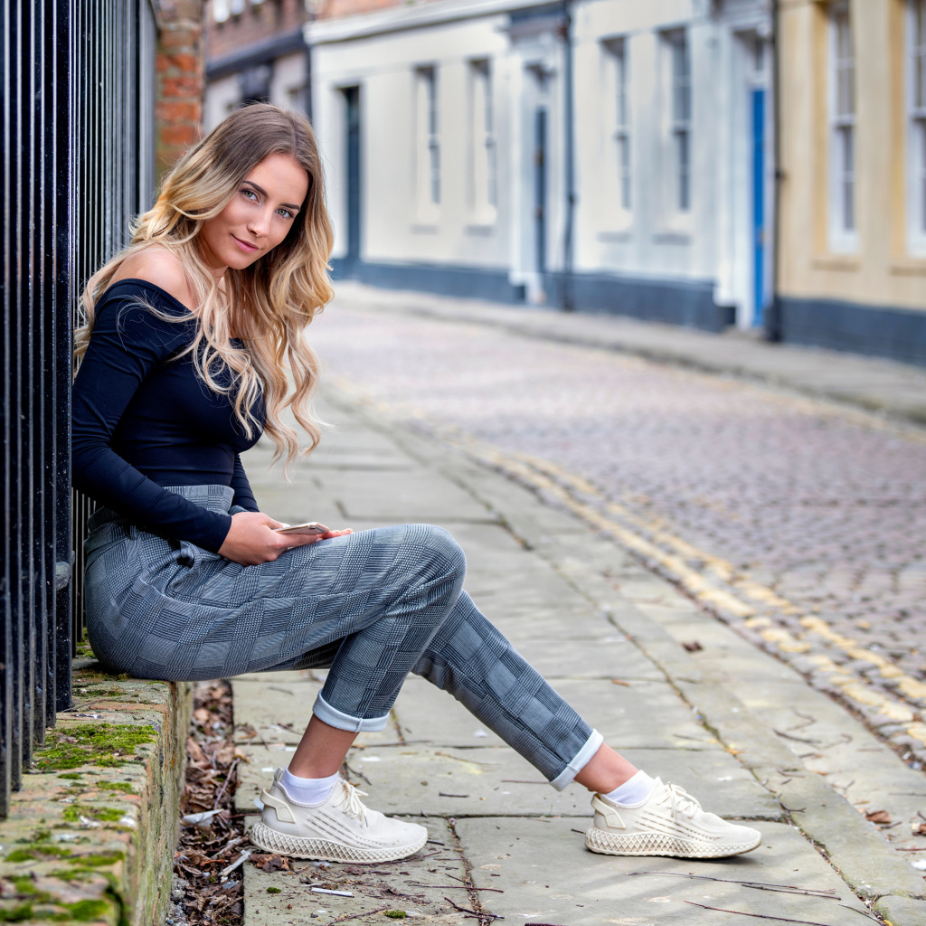 Красивая девушка блондинка сидит у забора