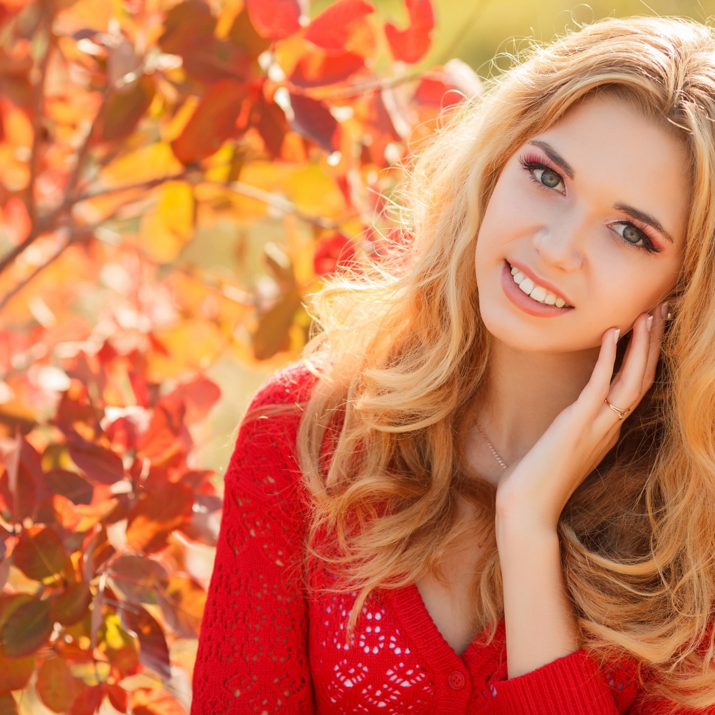 Beautiful blonde in a red sweater outdoors in autumn