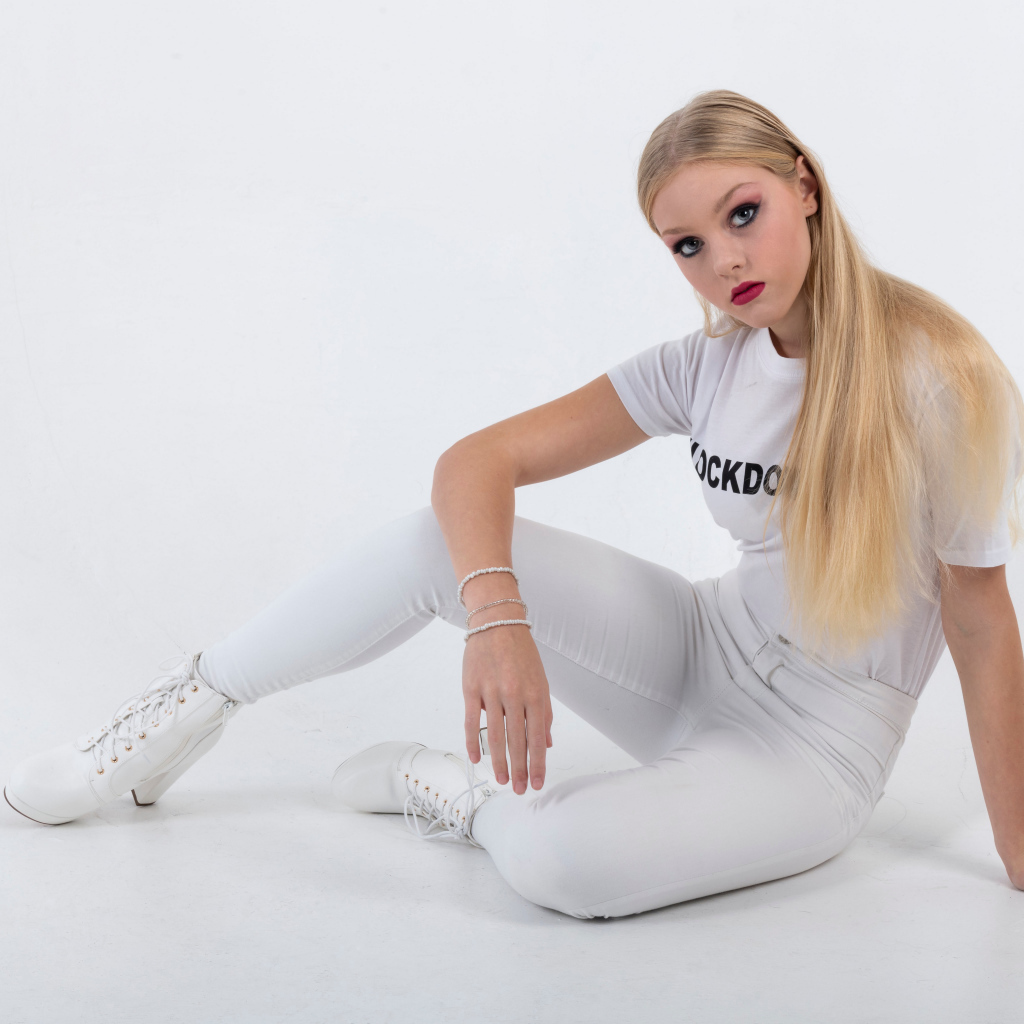 Красивая блондинка в белом костюме на сером фоне