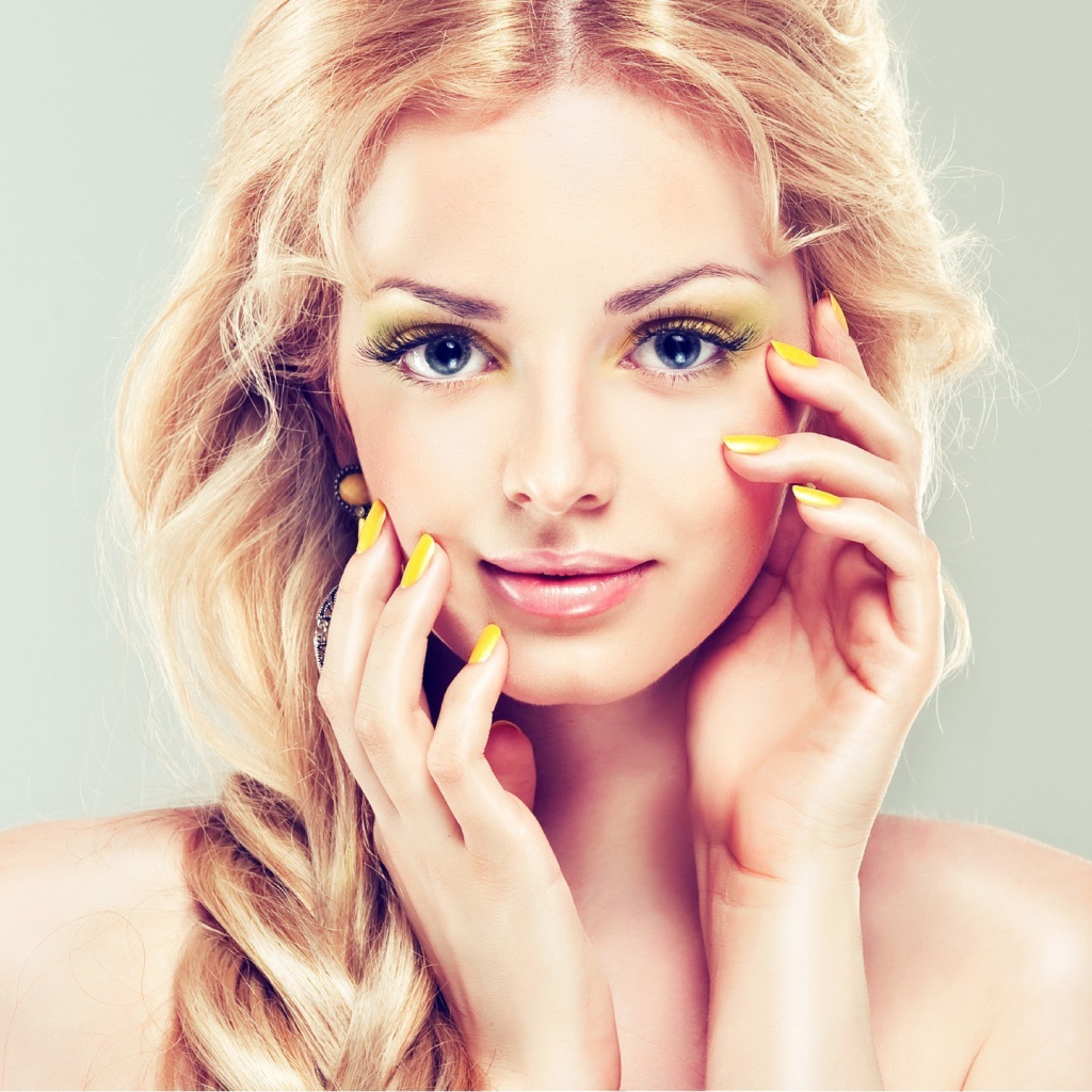 Красивая голубоглазая блондинка с желтым маникюром на руках 