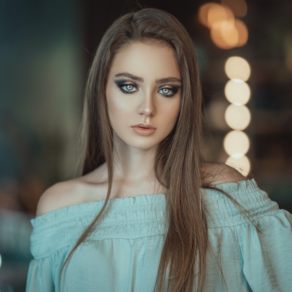 Красивая голубоглазая девушка в платье у зеркала 