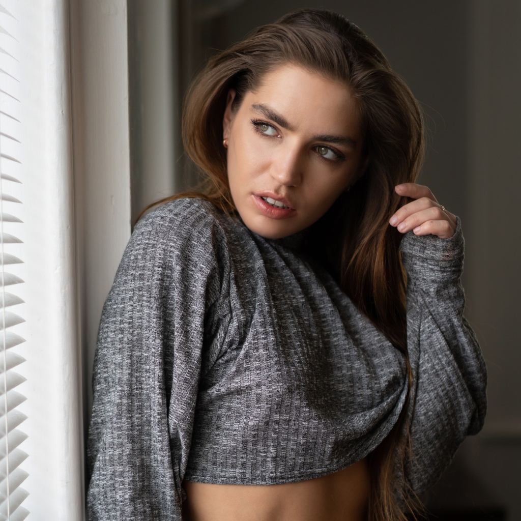 Красивая девушка брюнетка стоит у окна