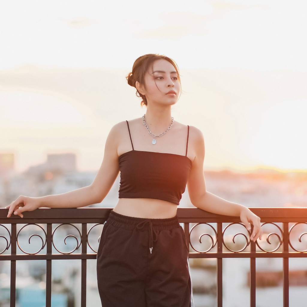 Красивая девушка в черном костюме на мосту в лучах солнца