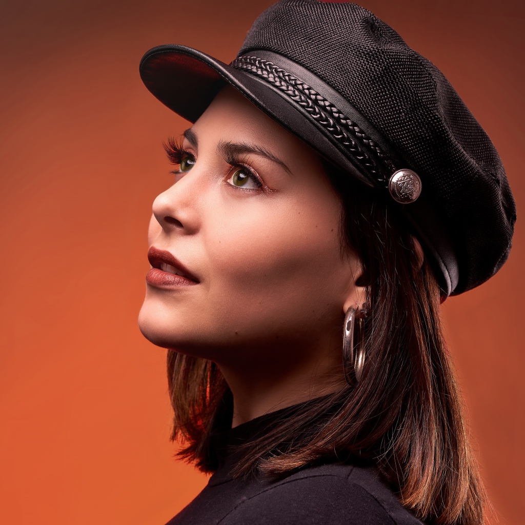 Красивая девушка в кепке на коричневом фоне