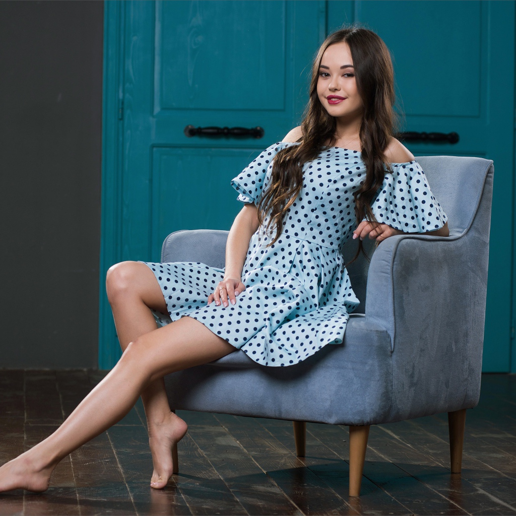 Красивая девушка в платье в горох на кресле