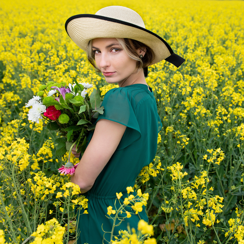 Красивая девушка в шляпе на поле с желтыми цветами летом