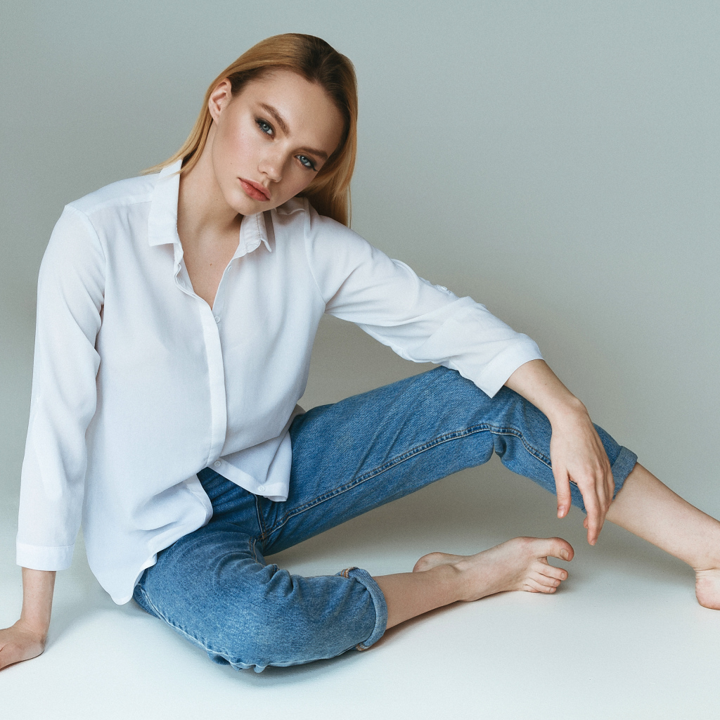 Красивая девушка в белой рубашке на сером фоне