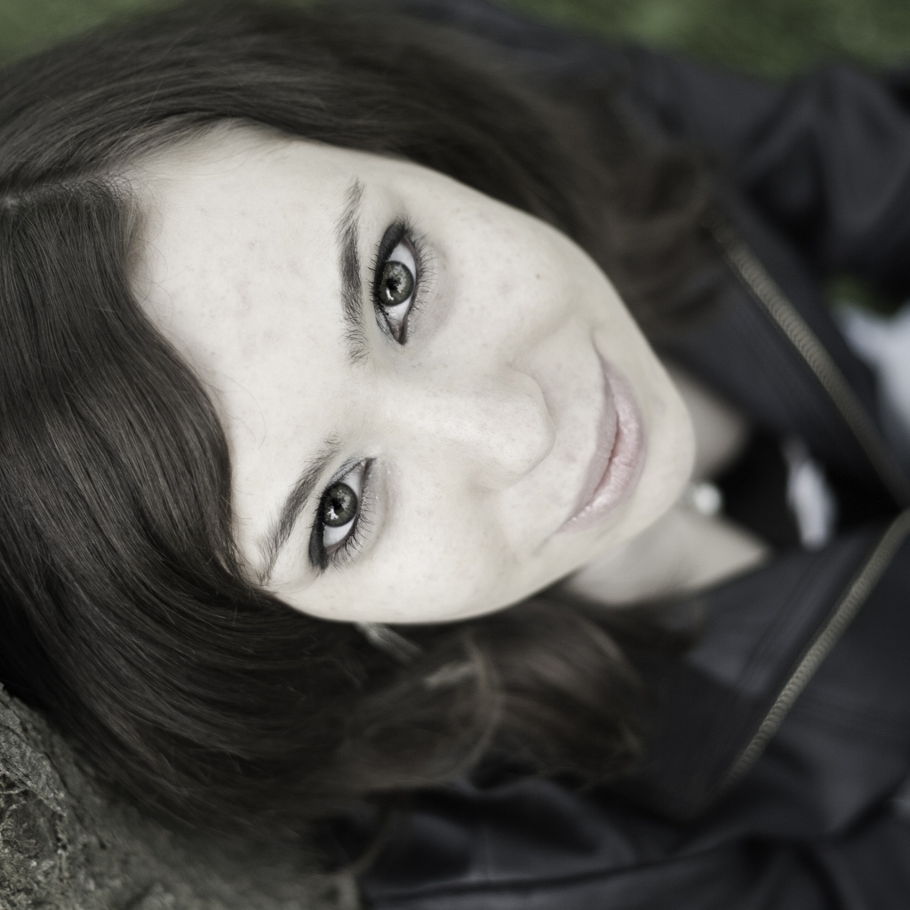 Красивая девушка смотрит вверх сидя под деревом  