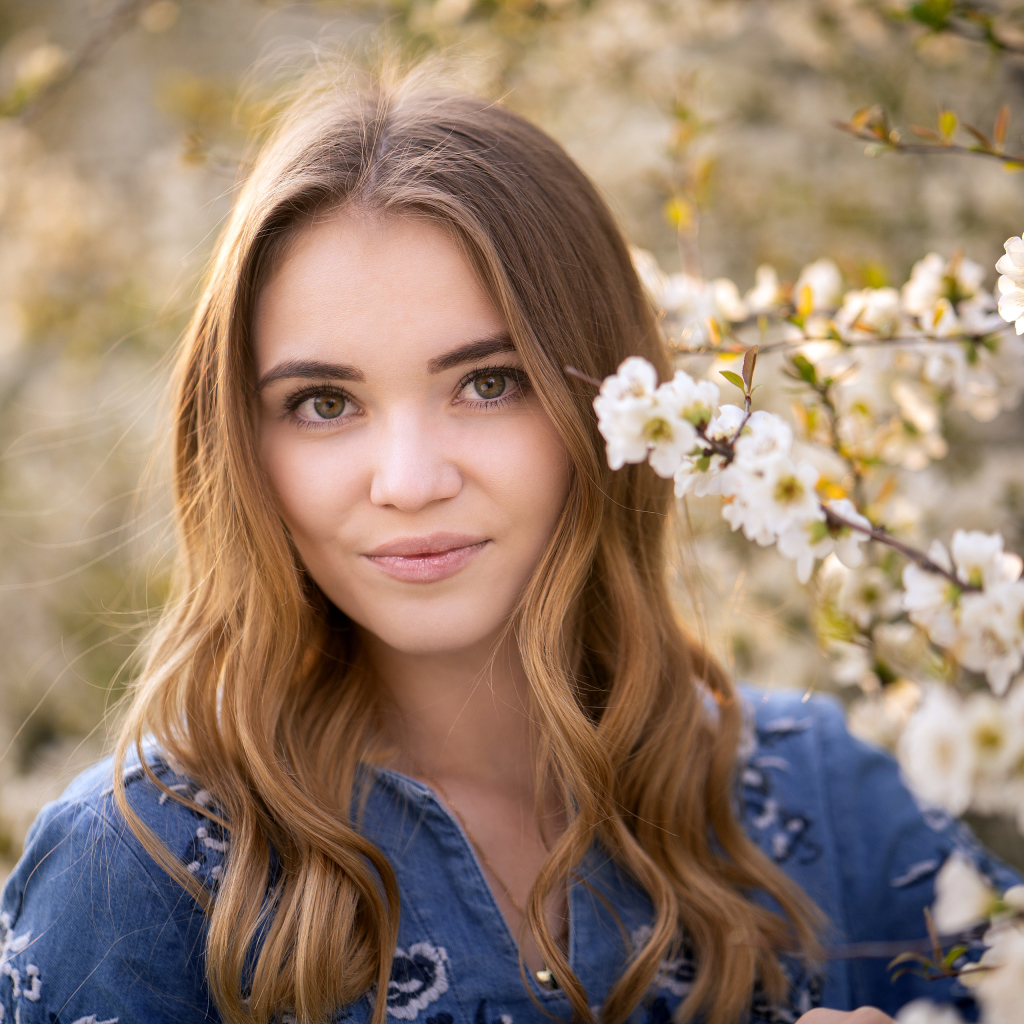 Красивая девушка у ветки с белыми цветами