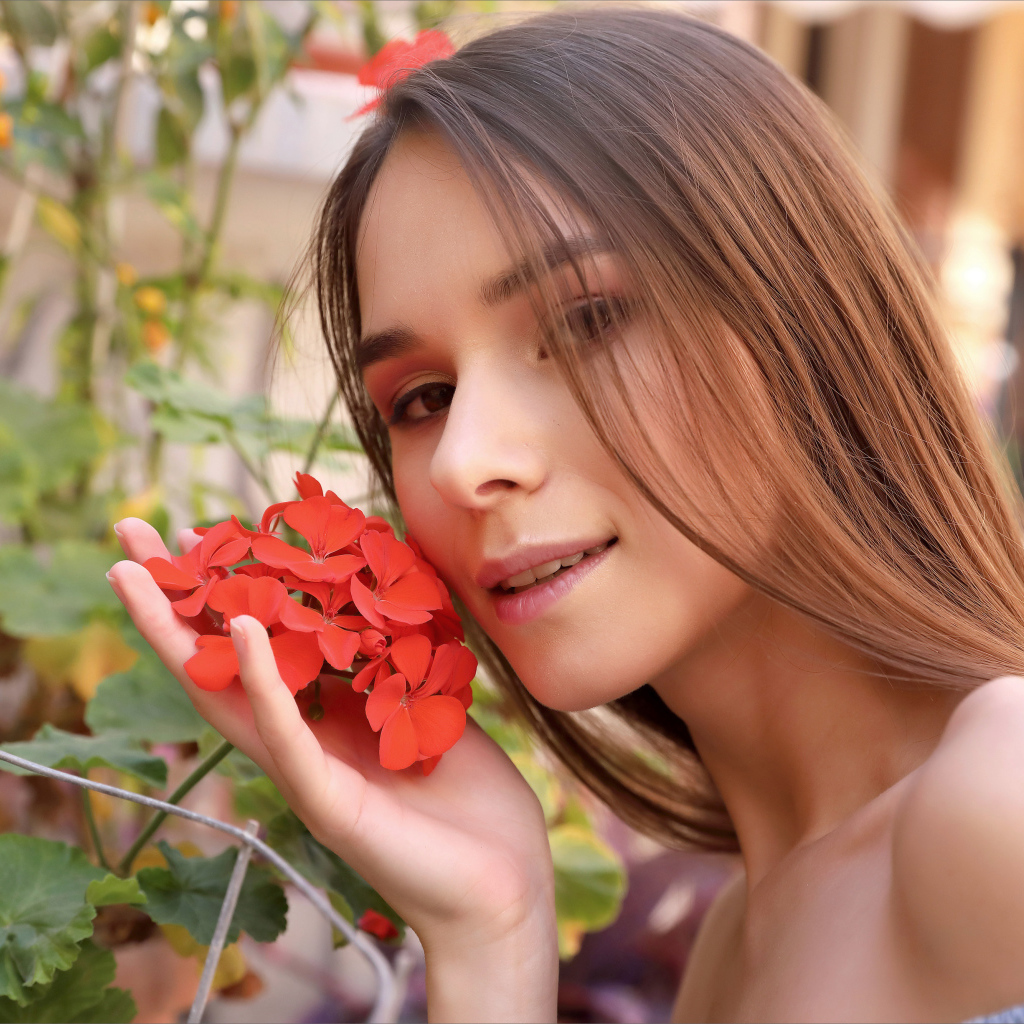 Красивая девушка с красным цветком герани 