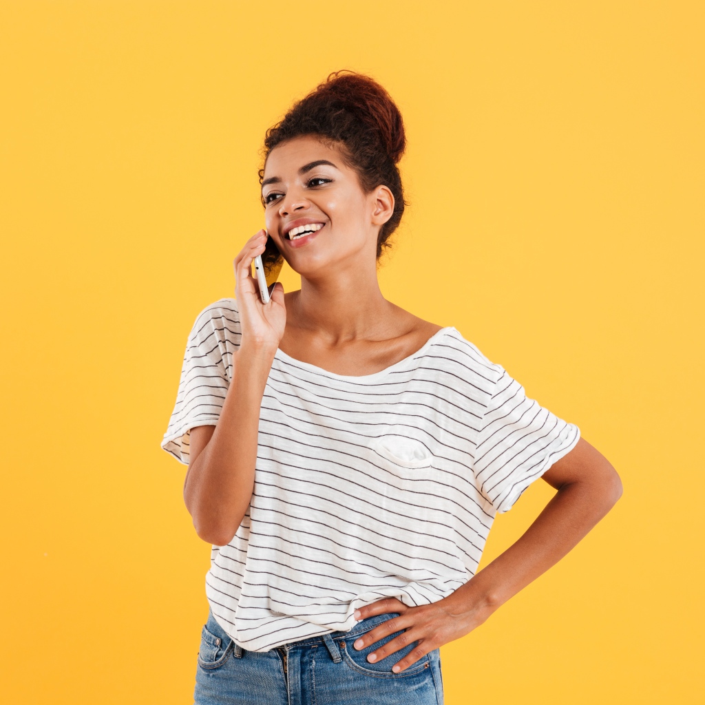 Красивая девушка со смартфоном на желтом фоне