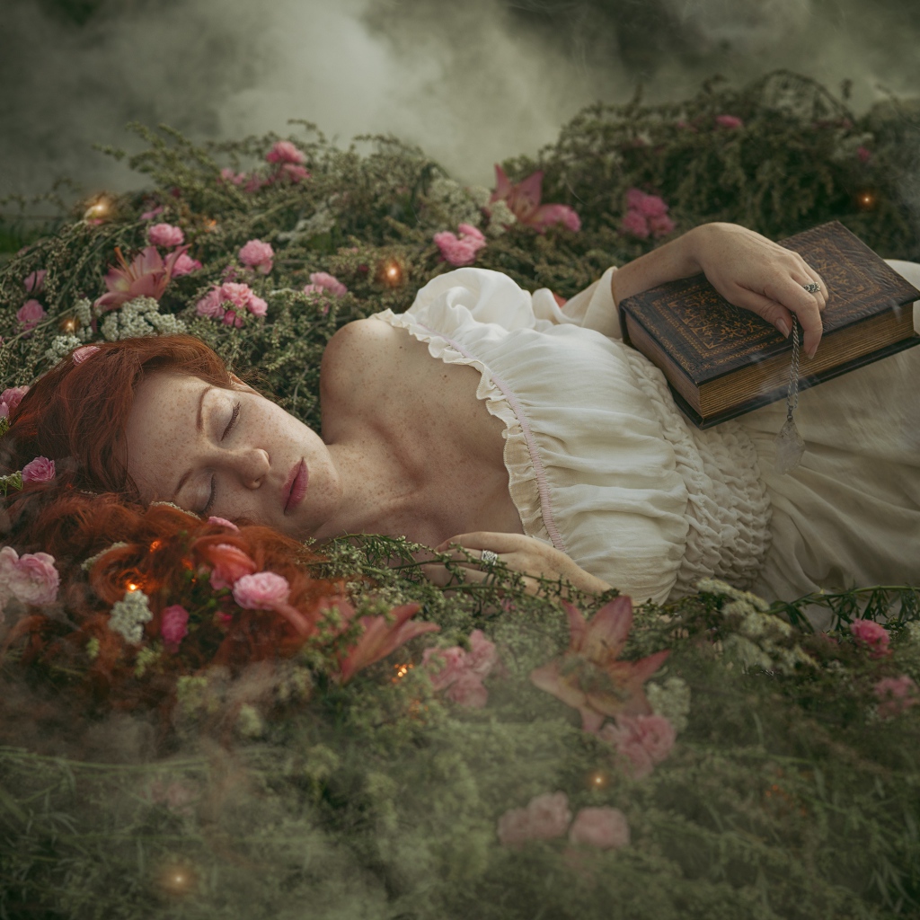 Красивая рыжеволосая девушка спит на земле с книгой