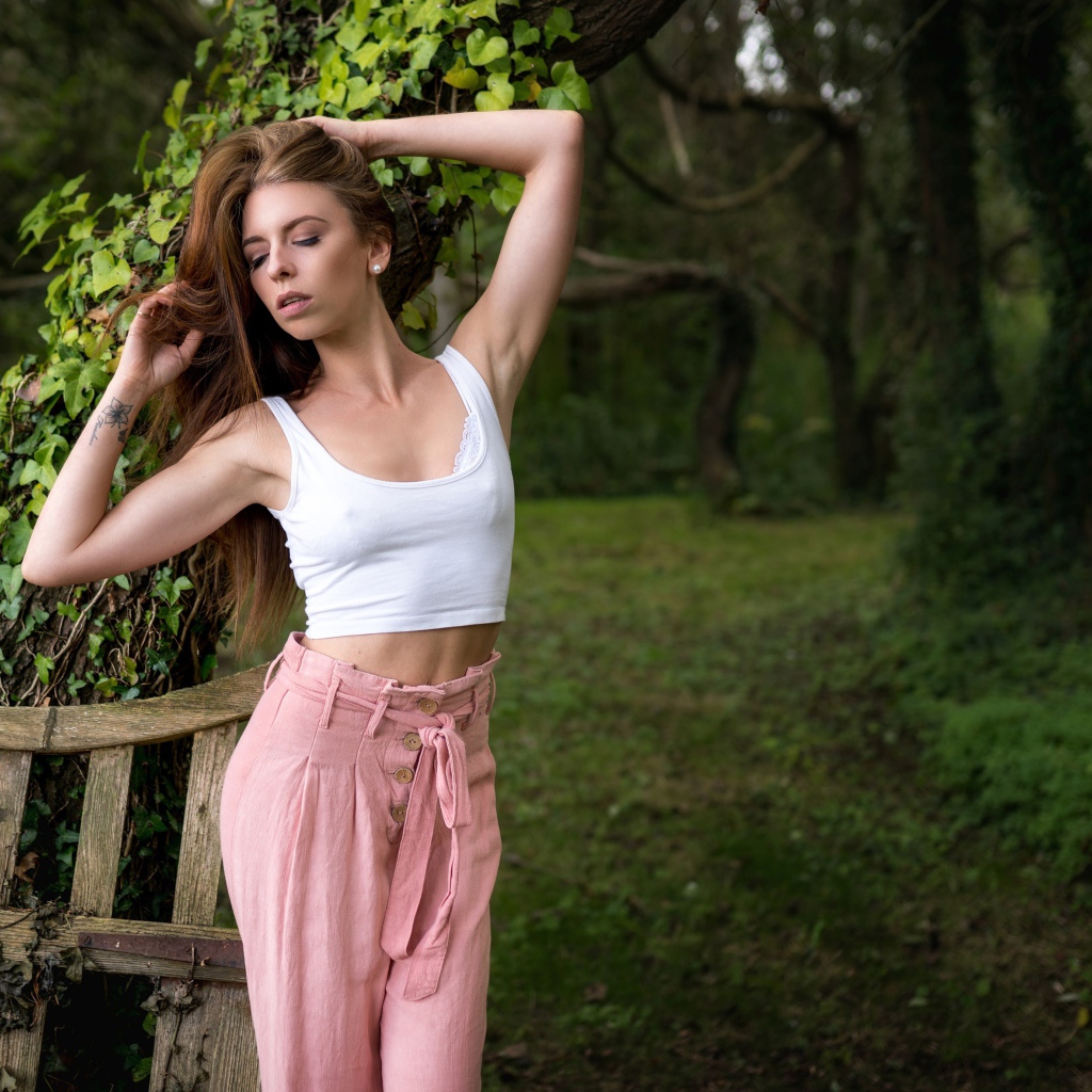 Красивая стройная девушка стоит у дерева 