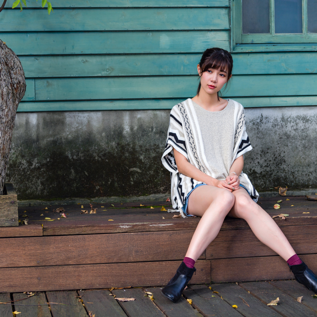 Красивая молодая девушка азиатка сидит у дома