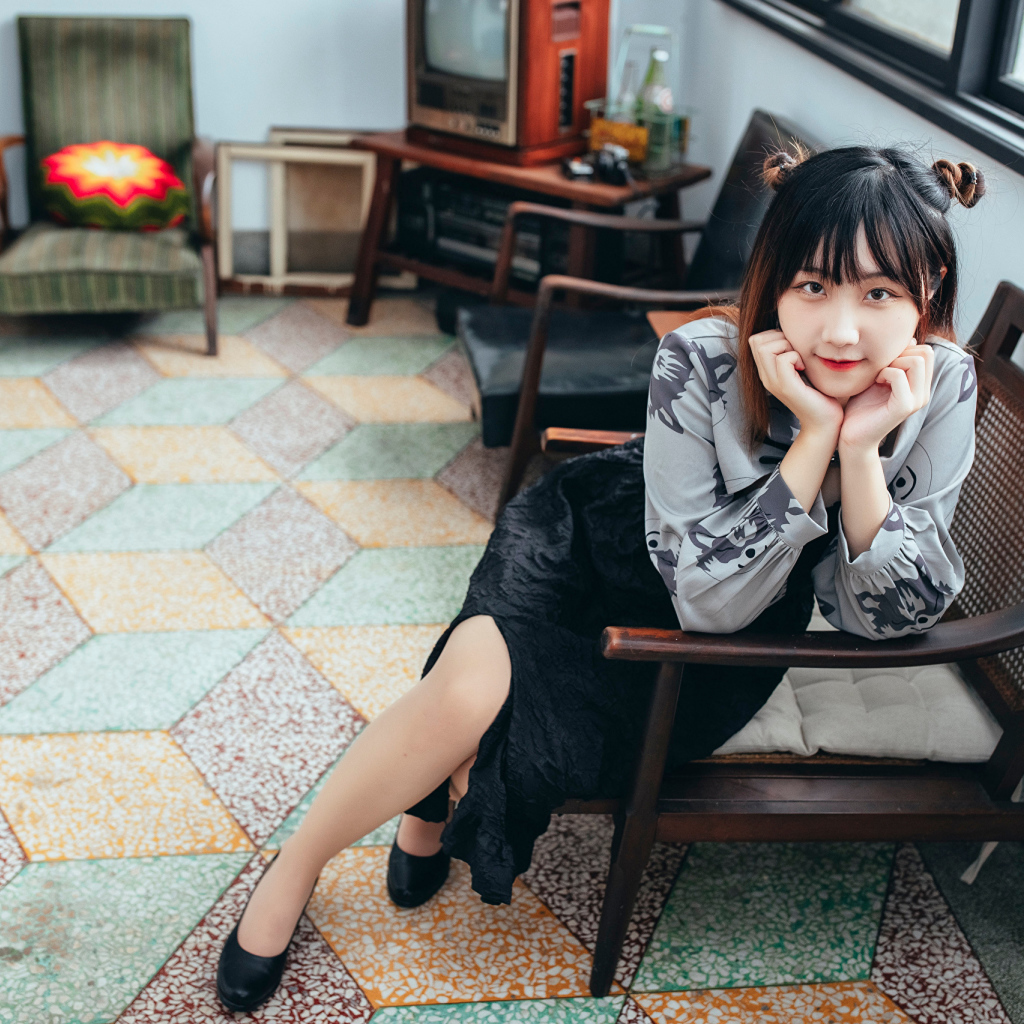 Красивая молодая азиатка сидит в кресле